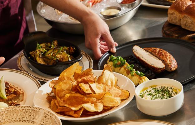 A chef setting down plates on a full table.