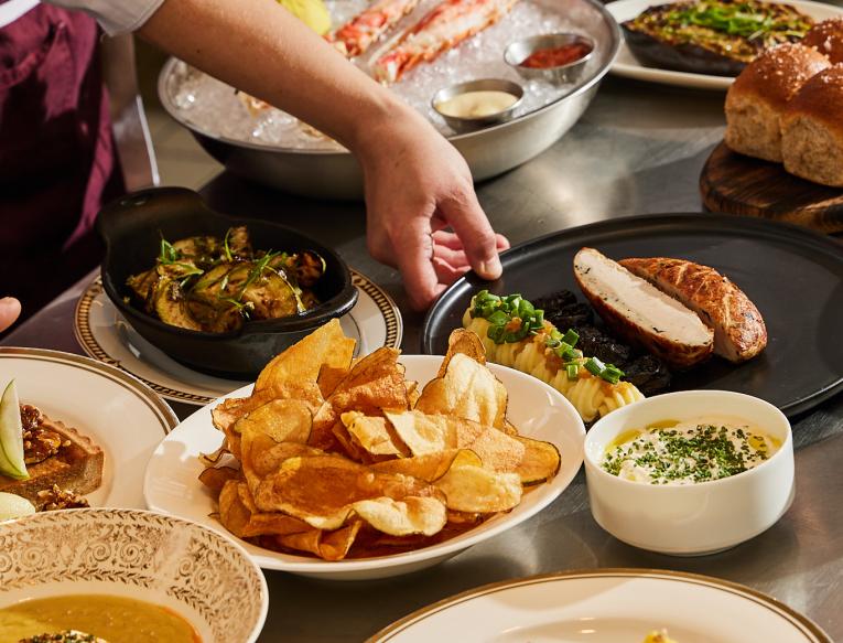 A chef setting down plates on a full table.